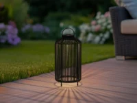 Origin 21 25-inch black metal solar outdoor decorative lantern glowing on backyard patio at night